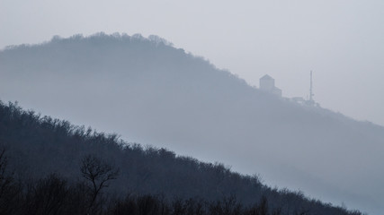 Fototapeta premium Medieval castle on the side of the mountain in fog
