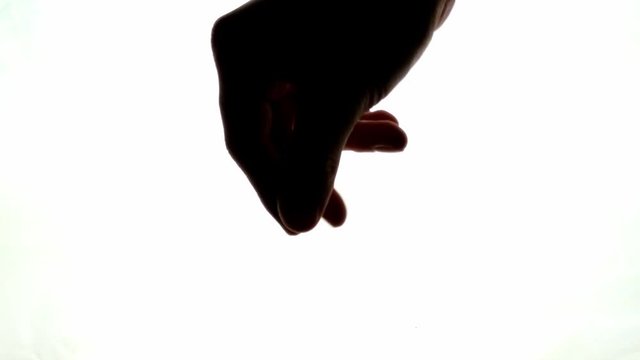 Silhouette of a hand pointing downwards and rubbing fingers and thumb together like pouring a powder or trying to wipe away dirt