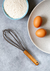 Silicone whisk with wooden handle, eggs and flour 