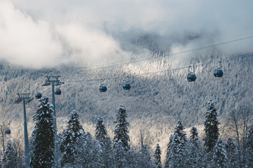 Winter Mountain landscape at the Rosa Khutor ski resort in Sochi, Russia. Cable car cabin over pine trees in the snow