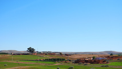 Obraz premium Bright landscape of Morocco, breathtaking curves of mountains, stunning combination of hills & farm land,inadvertent distribution of houses & huts, raw impression of pure nature.