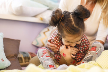 Cute daughter with funny hairdo surrounded with mother's hands