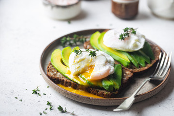 Healthy breakfast whole wheat toasted bread with avocado and poached egg over white background