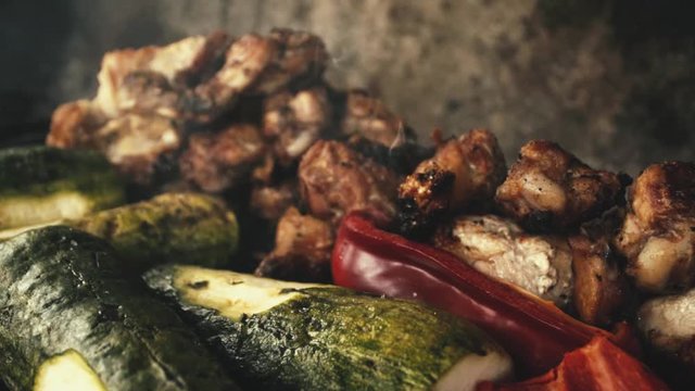 Slow-motion close-up chicken wings and grilled vegetables, (Italian squash and red pepper or red pepper / smoke from the charcoal grill).