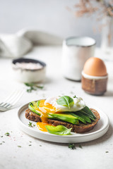 Healthy breakfast whole wheat toasted bread with avocado and poached egg over white background