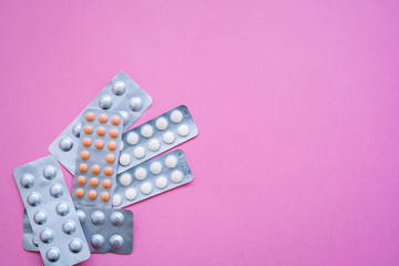 Different medicines - aluminium blister tablets of vitamins pills, tablets, capsules on pink background. Pharmaceutical Antibiotic, medicament. Pharmacy drugstore and health theme. Selective focus