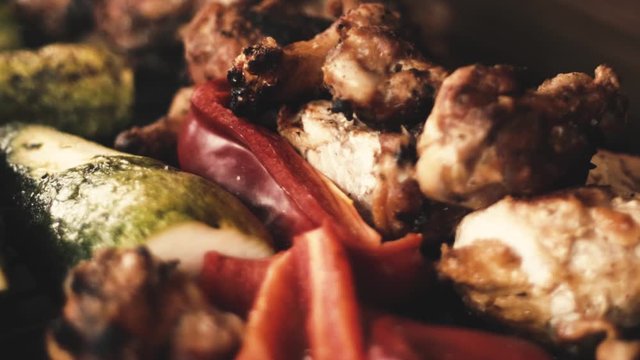 Slow-motion close-up chicken wings and grilled vegetables, (Italian squash and red pepper or red pepper / smoke from the charcoal grill).