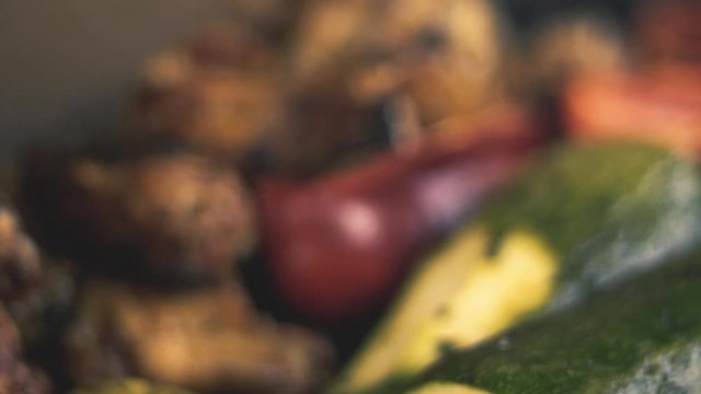 Slow-motion close-up chicken wings and grilled vegetables, (Italian squash and red pepper or red pepper / smoke from the charcoal grill).