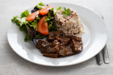 fried liver with salad and boiled rice on white plate