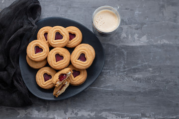 cookies with hearts on dark plate on ceramic background