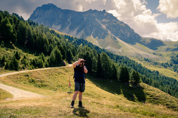 Fototapeta premium Photographer making a photograph high up in the Pennine Alps near the Swiss village of Saint-Luc in summer. Val d' Anniviers, Valais, Switzerland