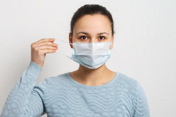 Studio portrait of young woman wearing a face mask, looking at camera, close up, isolated on gray background. Flu epidemic, dust allergy, protection against virus