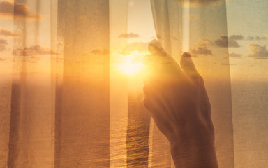 New day new life concept. Hand opening up Curtin window letting the morning sunshine in. 