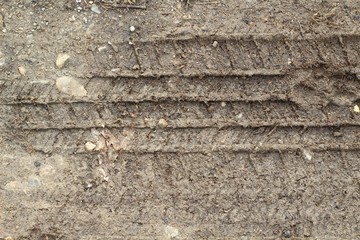 A close view of the tire print in the dirt ground surface.