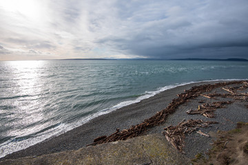 High angle seascape of beach, driftwood, water and clouds at Fort Casey State Park in Coupeville, Washington