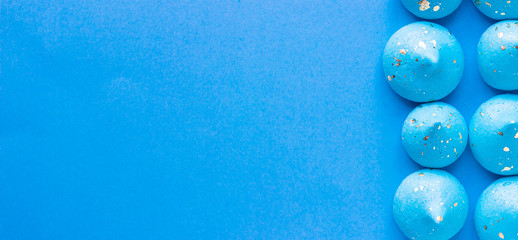 Blue mini meringue on a blue paper background. Dessert background.  - obrazy, fototapety, plakaty
