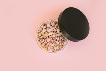 Natural sea salt mineral grains in a round container. Overview on pink background. Flat lay with beauty product.