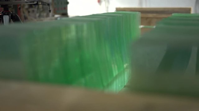 Focusing through a pile of clear glass panels on the shelf. Sheets of green tempered clear glass. Stack of glass sheets cut to size in glass factory. 