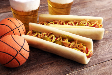 Grilled hot dogs with mustard and ketchup on the table with draft beer. Television watching...