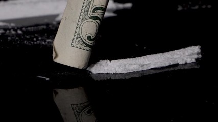 Snorting cocaine line with a rolled banknote, isolated on smooth black background. Close up, macro. Slow motion. - Powered by Adobe