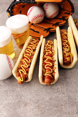 Grilled hot dogs with mustard and ketchup on the table with draft beer. Baseball party food with balls for the playoffs