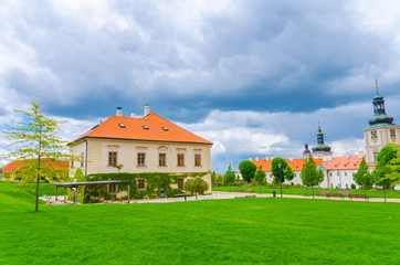 Fototapeta na wymiar Jesuit College building and green grass lawn of Park GASK in Kutna Hora historical Town Centre, blue dramatic sky background, Central Bohemian Region, Czech Republic