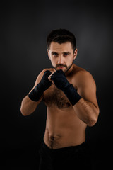 Fototapeta na wymiar Muscular boxing man ready to fight on black background