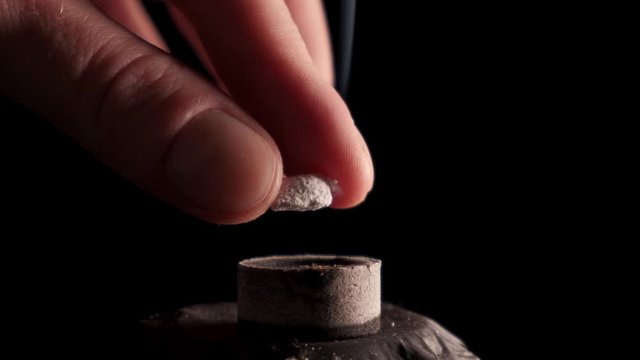 Incense on self-igniting charcoal, black background.