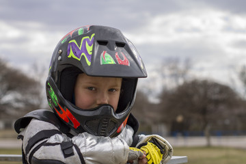 portrait of a little girl in a protective helmet and protective clothing in armor and beslessy gloves, female child in motocross helmet