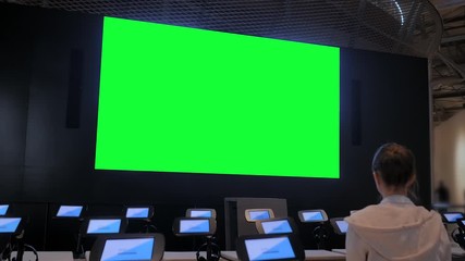 Green screen, technology, chroma key, futuristic, template, mock up, education concept. Woman looking at large wall blank interactive green display at modern science center, exhibition or museum