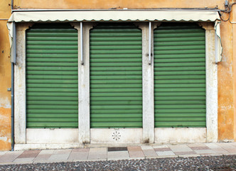 Old closed green metal rolling shutters on an old building