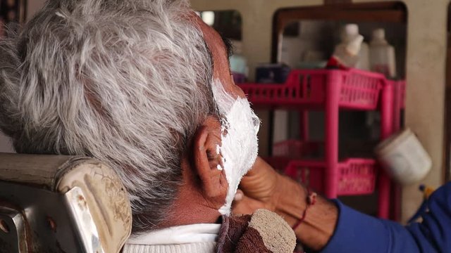 Barber Applied  Shaving Foam By A Swab To The Face Of An Old Man, Man Doing Shaving In Barber Shop.Close-up Shot.