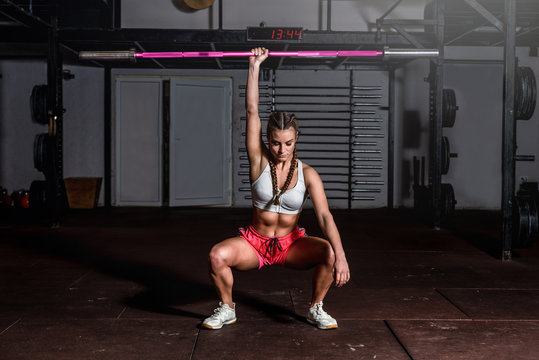 Young beautiful attractive muscular and strong fit girl holding heavy barbell weight with her one hand ready for snatch hardcore cross weightlifting workout training in the gym real people