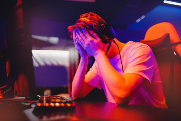 Gamer young man is defeated in online video game, anger and facepalm, screaming and emotion, neon...