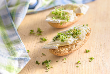 Ein belegtes Brötchen mit Cemembert und Kresse