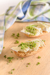 Ein belegtes Brötchen mit Cemembert und Kresse