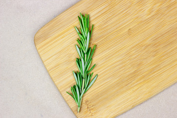 Top view of bright fresh green rosemary branches, twigs and leaves on a wooden board on light background.