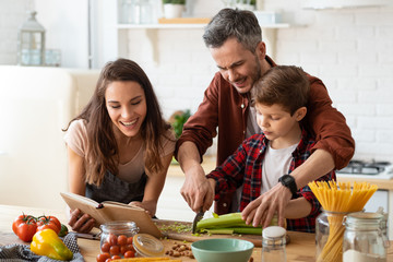 Mother, father, son chopping vegetables on kitchen