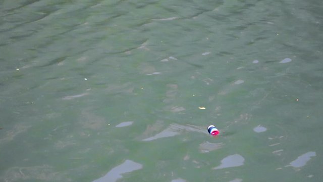 Fishing lure bobbing on water being dragged across. locked off