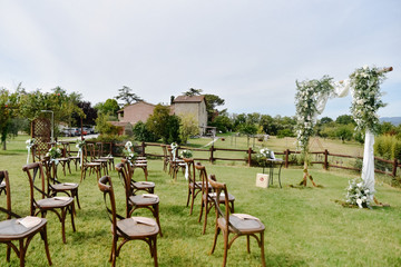 Guest seats in front of building made of stone in garden and decorated ceremonial wedding arch