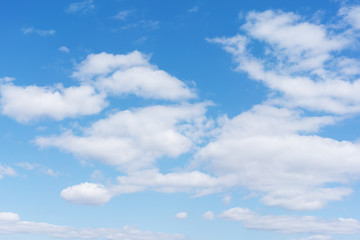 White cumulus clouds against the background against blue on a blue background.