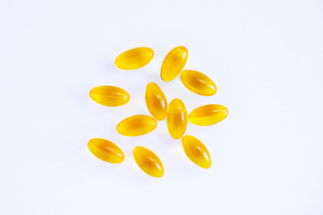 Yellow capsules with oil on a white background. Medicines and nutritional supplements.