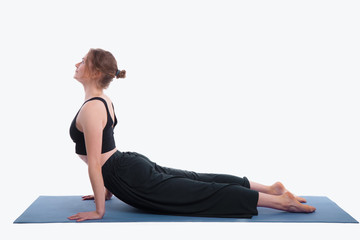 Portrait of gorgeous young woman practicing yoga indoor. Beautiful girl practice cobra asana in studio on white background.Calmness and relax, female happiness.