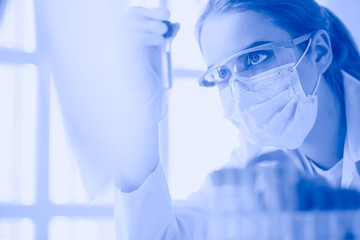 Portrait of pretty female laboratory assistant analyzing a blood sample at hospital