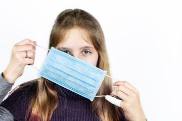 Medical mask on the face of a teenager girl. The girl puts on a mask to prevent colds and viruses