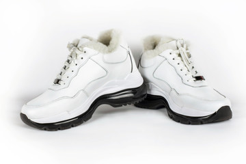 White warm women's sneakers on a light background. Such shoes are warm and comfortable to walk long distances in the cold seasons