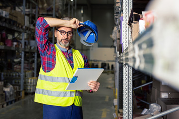 Male warehouse worker with clipboard. Warehouse worker hand holding clipboard.