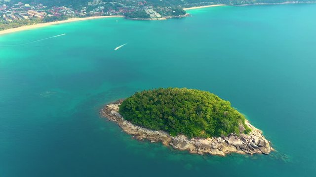 Nice rocks forested island, aerial panorama of Ko Pu against mountainous Phuket landscape on background. Deep tropical jungle thicket covering stony islend.Boat sailing. Aerial