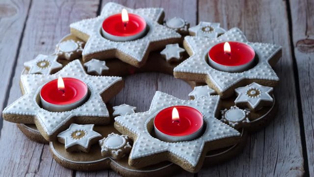 Christmas advent wreath of star-shaped gingerbread with burning red tea candles - Powered by Adobe