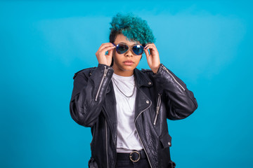 girl with blue afro american hair sunglasses isolated on blue background with fur jacket